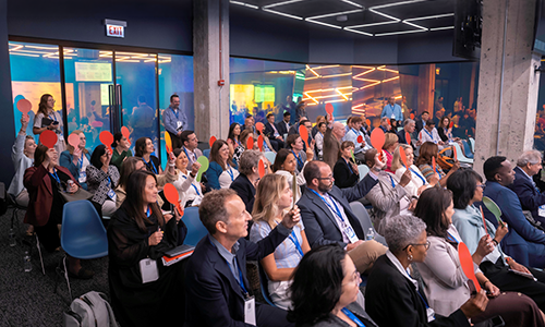 Audience 2 – CareQuest Innovation Partners Audience at a conference, many people seated and raising hands to ask questions or participate.